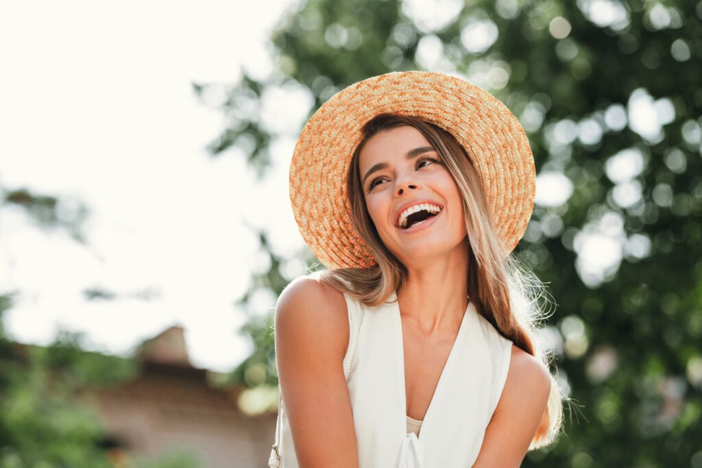 Woman smiling outdoors in a sun hat